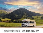 Scenic view big modern white family rv camper van vehicle drive Europe highway road alpine mountain cloud in summer day. Rving motorhome lifestyle travel adventure tourism trip Alps journey concept