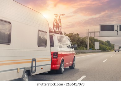 Scenic view big modern white family rv camper van vehicle driving on european highway road against sunset sun sky summer. Rving motorhome rent lifestyle travel adventure tourism trip journey concept