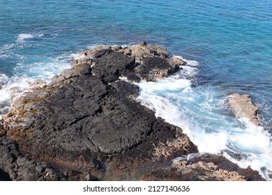 A Scenic View Of Black Volcanic Rock On The Ocean Water's Edge In Kona, Hawaii