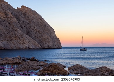 A scenic view of a boat sailing in the ocean during a beautiful sunset in Oia, Santorini - Shutterstock ID 2306676903