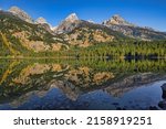 A scenic view of Bradley Lake reflecting the Grand Teton Mountains in Wyoming, USA on a sunny day