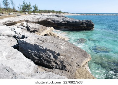 The scenic view of breaking apart rocky coastline and a warning sign on Grand Bahama island.