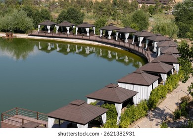 Scenic view of a calm lake with cozy lakeside cottages and a charming restaurant surrounded by nature. The peaceful landscape reflects beauty, architecture, and harmony in a serene setting.