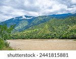 Scenic view of the Cauca River in Santa Fe de Antioquia, Colombia, with lush green mountains under a cloudy sky