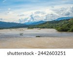 Scenic view of the Cauca River in Santa Fe de Antioquia, Colombia, with lush green mountains under a cloudy sky