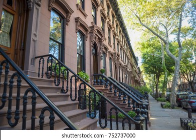 Scenic View Of A Classic Brooklyn Brownstone Block With A Long Facade And Ornate Stoop Balustrades On A Summer Day In New York City