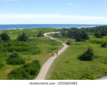 Scenic view of coastal path with people walking, lush greenery leading to the ocean on a sunny day at Greenwich National Park on Prince Edward Island - Powered by Shutterstock