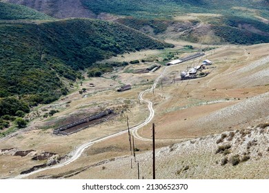 Scenic View Of Dirt Road And Farmhouses In A Mountain Ravine