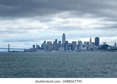 Scenic view of downtown San Francisco with skyline and San Francisco-Oakland Bay Bridge, California, USA seen from the water against cloudy sky - Powered by Shutterstock