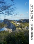 Scenic view of dramatic coastal cliffs with houses overlooking the ocean in New South Wales, Australia. The rugged landscape, crashing waves, and greenery highlight the beauty of Australia’s coastline