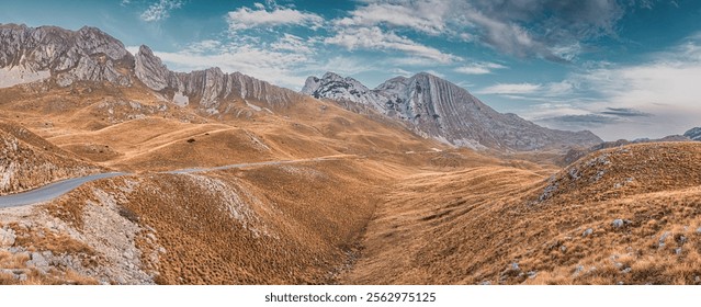 Scenic view of Durmitor national park with a winding road leading towards Bobotov Kuk mountain range under a cloudy sky, travel in Montenegro