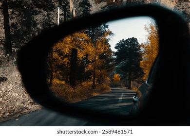 A scenic view of fall trees viewed through rear view mirror in Colorado