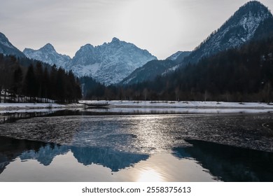 Scenic view of frozen lake Jezero Jasna in Kranjska Gora along road to Vrsic Pass in winter. Reflection of snow capped mountains of Julian Alps, Slovenia. Warm glow creates tranquil serene atmosphere - Powered by Shutterstock