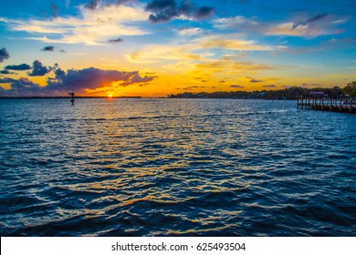 Scenic View Of A Golden Sunrise Over The St Lucie Inlet In Florida From The River With Channel Markers And Piers.