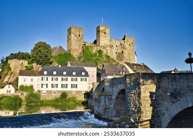 Scenic view of a historic castle and old stone bridge in a European village under a clear blue sky. - Powered by Shutterstock