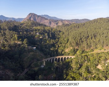 A scenic view of a historic railway viaduct nestled in lush green mountains. - Powered by Shutterstock