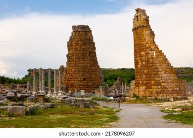 Scenic view of historical remains of two stone towers of Hellenistic gate and colonnaded street of empty ancient city of Perge on sunny spring day, Antalya province, Turkey Scenic view of historical remains of two stone towers of Hellenistic gate and colonnaded street of empty ancient city of Perge on sunny spring day, Antalya province, Turkey