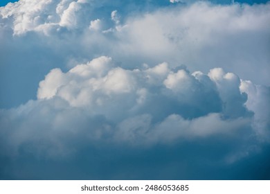 Scenic view to huge dramatic white clouds in blue sky. Nature background of fluffy cloudiness. Beautiful minimalist cloudscape. Nature texture of cloudy skies. Minimal skyscape in changeable weather.