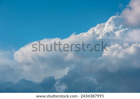 Scenic view to huge dramatic white clouds in blue sky. Nature background of fluffy cloudiness. Beautiful minimalist cloudscape. Nature texture of cloudy skies. Minimal skyscape in changeable weather.