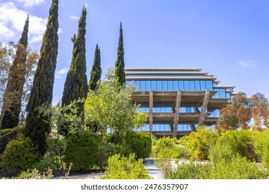 A scenic view of the iconic Geisel Library at UC San Diego, surrounded by lush greenery and tall cypress trees.