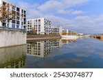 Scenic view of lake with reed and modern apartment buildings with blue cloudy sky on an autumn day at Swiss town of Opfikon Glattbrugg. Photo taken November 8th, 2024, Zurich Opfikon, Switzerland.