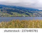 Scenic view of Lake Sarnen on a sunny autumn day with woodland and mountain panorama in the background. Photo taken October 17th, 2023, Sachseln, Canton Obwalden, Switzerland.