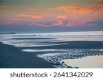 A scenic view of lingering tidal pools at Myrtle Beach, SC by the Apache Pier just before sunrise