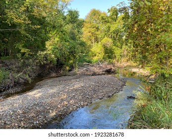 scenic view looking down at lush foliage surrounding a rushing river bed creek brook and blue sky