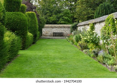 Scenic View Of A Lush Green Grass Path Lined By Flowers In Bloom In An English Style Landscape Garden