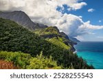 A scenic view of the lush Na Pali coastline along the Kalalau hiking trail on a mostly sunny day on Kauai, Hawaii