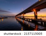 A scenic view of the Max Brewer Bridge and its reflection on water during sunrise in Titusville, Florida