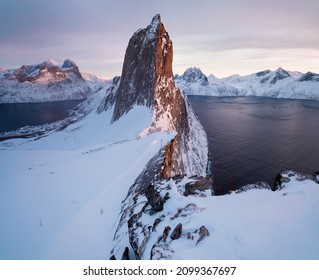 Scenic View from Mount Hesten on Iconic Mountain Segla at dawn in winter with snow in front of colorful sky and mountain range in background, Fjordgard, Mefjorden, Senja, Norway