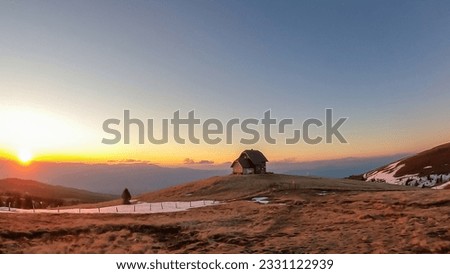 Scenic view of mountain hut Wolfsbergerhuette (Wolfsberger Huette) during sunrise on Saualpe, Lavanttal Alps, Carinthia, Austria, Europe. Snow covered meadow leading to remote alpine cottage