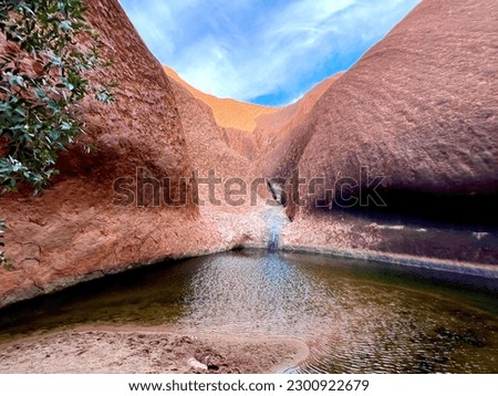 A scenic view of the Mutitjulu Waterhole below Uluru in Petermann, Australia