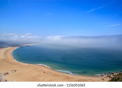 Scenic View Of Nazare Beach. Coastline Of Atlantic Ocean. Portuguese Seaside Town On Silver Coast. The Clouds Above The Water Are Like Tsunami Waves. Nazare, Portugal. Summer Sunny Day. 