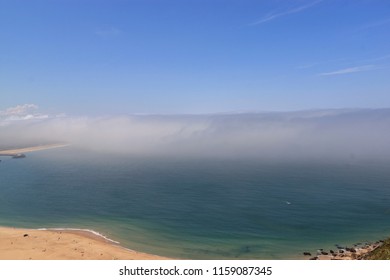 Scenic View Of Nazare Beach. Coastline Of Atlantic Ocean. Portuguese Seaside Town On Silver Coast. The Clouds Above The Water Are Like Tsunami Waves. Nazare, Portugal. Summer Sunny Day. 