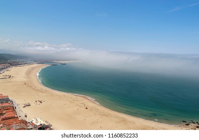 Scenic View Of Nazare Beach. Coastline Of Atlantic Ocean. Portuguese Seaside Town On Silver Coast. The Clouds Above The Water Are Like Tsunami Waves. Nazare, Portugal. Summer Sunny Day. 