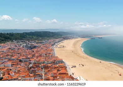 Scenic View Of Nazare Beach. Coastline Of Atlantic Ocean. Portuguese Seaside Town On Silver Coast. The Clouds Above The Water Are Like Tsunami Waves. Nazare, Portugal. Summer Sunny Day. 