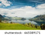 Scenic view on Vierwaldstättersee (Lago dei Quattro Cantoni, Lago di Lucerna, Lai dals Quatter Chantuns) with lake, snowy mountians, blue sky, clouds, meadows and forests from Emmetten, Switzerland