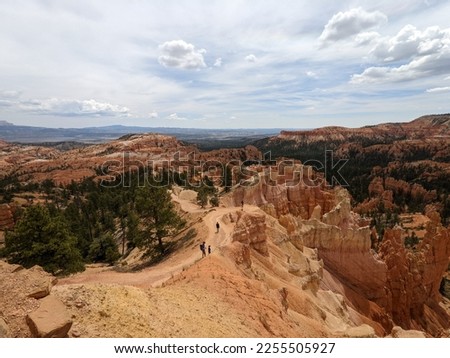 Scenic view of orange, red and white column rocks at Bryce Canyon National Park. Green trees, hiking path and hikers on Queens Garden Trail within the hoodoos, spires and sandstone.