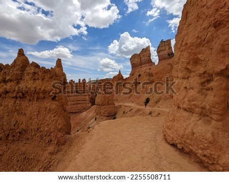 Scenic view of orange, red and white column rocks at Bryce Canyon National Park. Hiking path and hiker on Queens Garden Trail within the hoodoos.