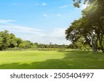 Scenic view of the park with green grass field in city and a cloudy blue sky background. Beautiful green park