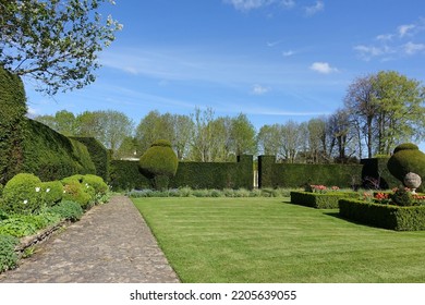 Scenic View Of A Path Through A Beautiful Landscape Garden With A Green Lawn, Flower Beds And Leafy Trees