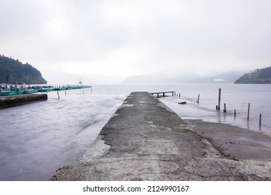 Scenic View Of Pier And Fishing Boat At Lake Ashi In Hakone, Japan With Mountain And Fog And Cloudy Sky Background. No People.