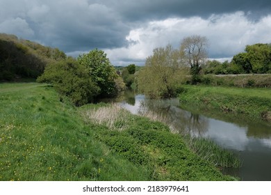 Scenic View Of A River Running Past Green Fields