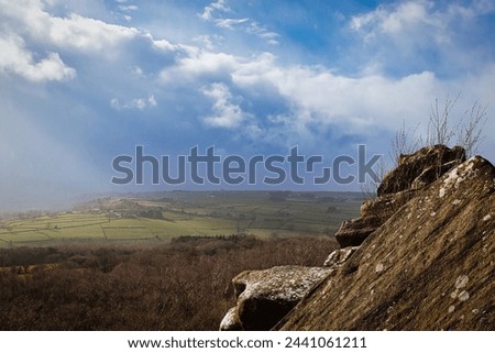 Scenic view from a rocky outcrop overlooking a lush valley under a dramatic cloudy sky at Brimham Rocks, in North Yorkshire