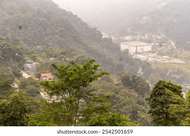 A scenic view of Rorathang, Sikkim, showcasing a lush green landscape, winding roads, and scattered buildings amidst misty mountains. - Powered by Shutterstock