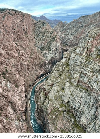 Scenic view of a rugged canyon with a winding river flowing between towering rock walls under a cloudy sky