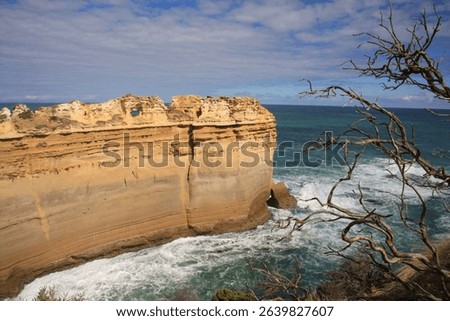 Scenic view of rugged cliffs and ocean waves at Loch Ard Gorge, Great Ocean Road, Australia, under a partly cloudy sky.
