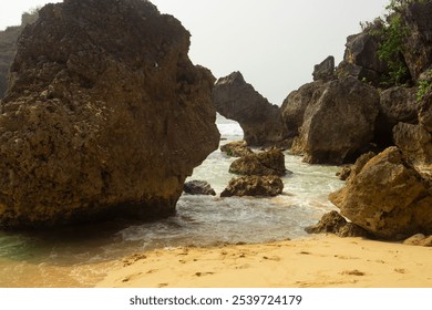 A scenic view of rugged coastal rocks framing the ocean, with waves gently crashing against the shore. This image captures the raw beauty and tranquility of a secluded beach landscape - Powered by Shutterstock